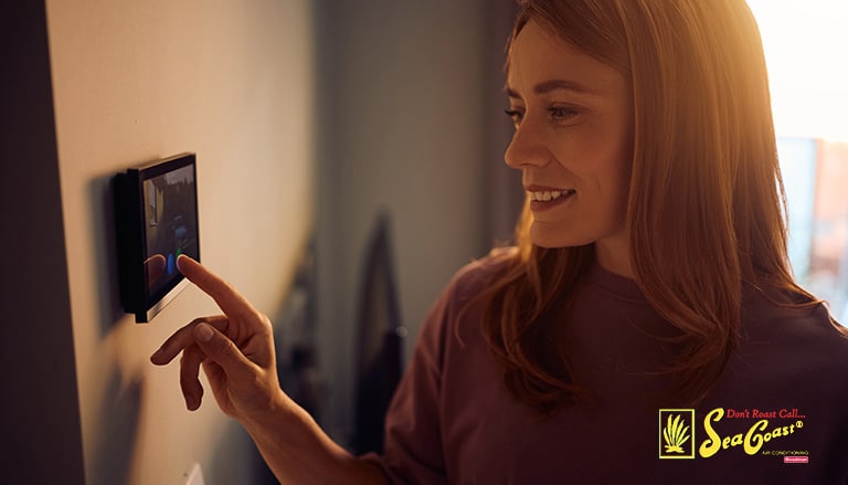 a homeowner setting her smart thermostat