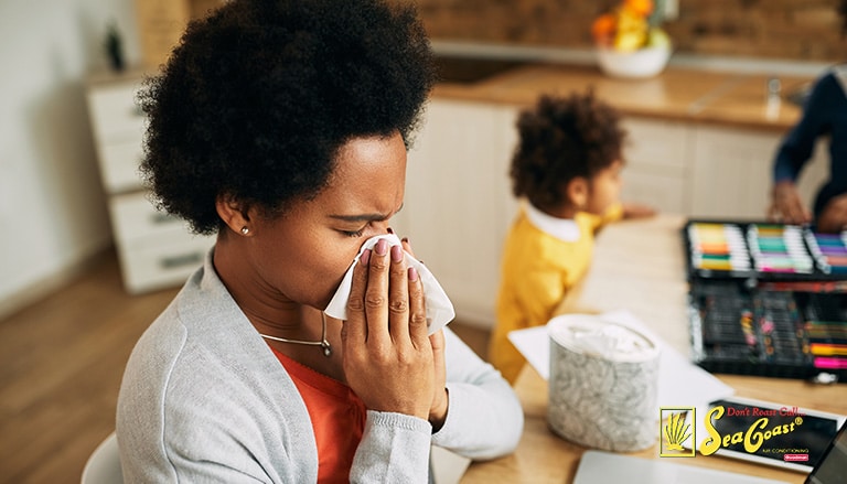 woman sneezing into a tissue